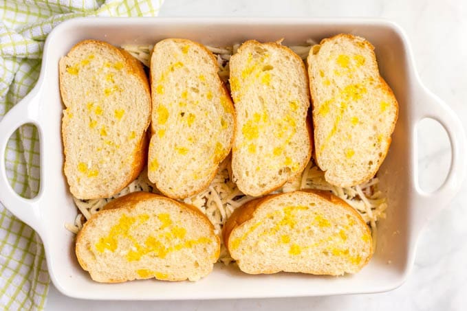 Cheesy sloppy Joe casserole before baking with bread on top drizzled with olive oil