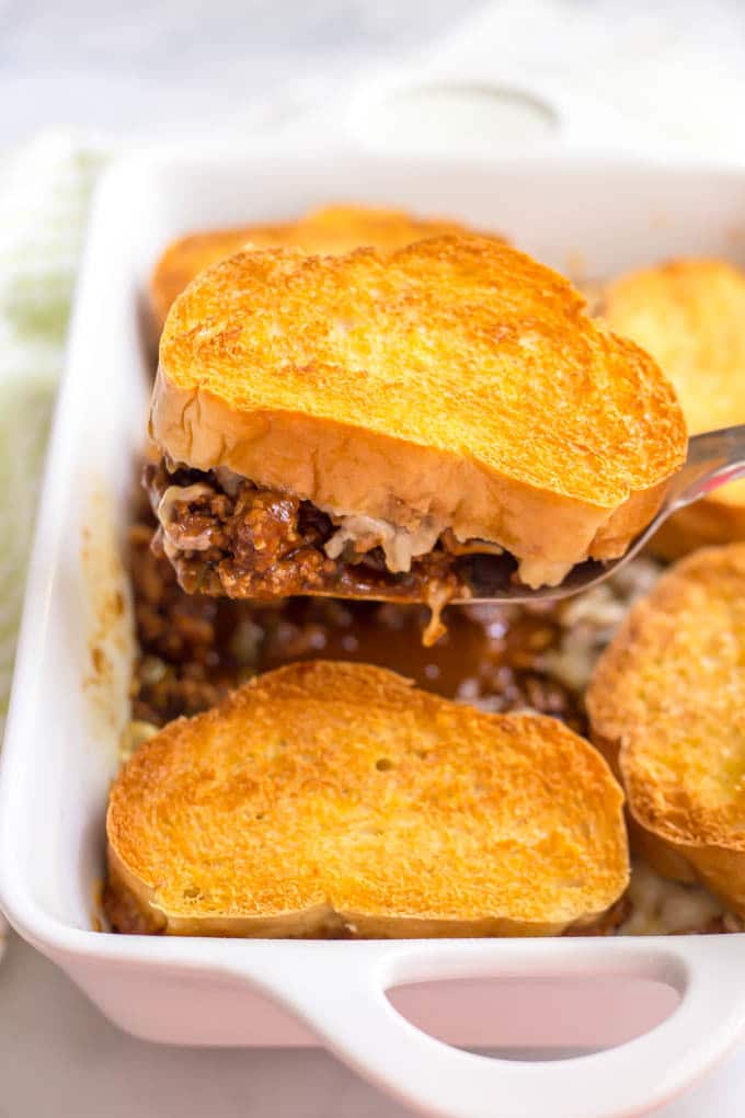 A spatula lifting a section of cheesy sloppy Joe casserole out of casserole pan