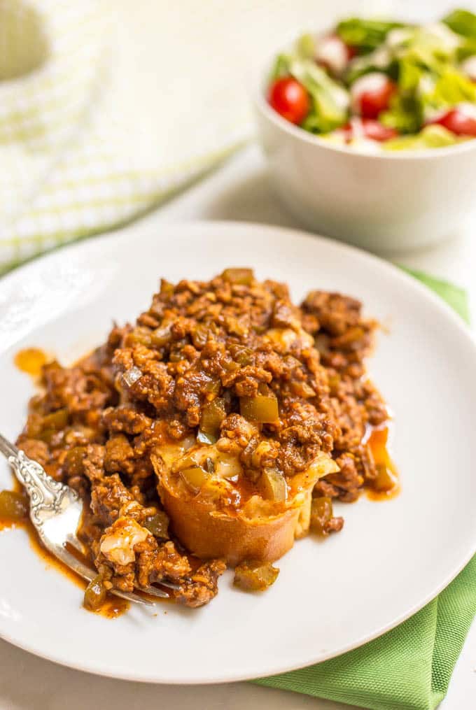 Cheesy sloppy Joe casserole served on plate with a side salad in a bowl in background