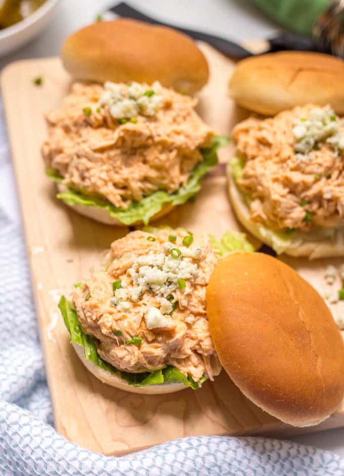 A small wooden board with three buffalo chicken sliders