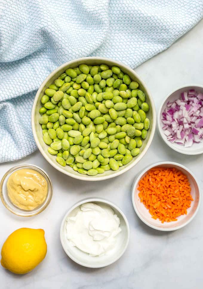 Ingredients in white bowls to make smashed edamame salad