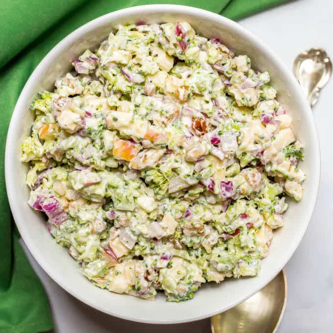 Healthy broccoli apple salad with dressing mixed in white bowl