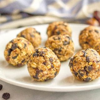 No bake blueberry oatmeal cookie balls on plate with scattered dried blueberries