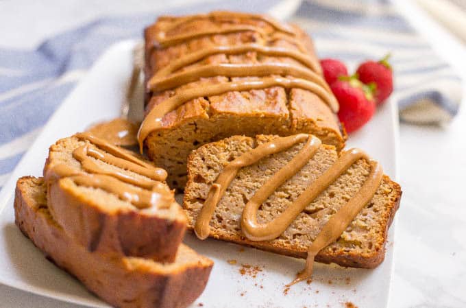 Whole wheat peanut butter banana bread with drizzle of peanut butter over top and on slices