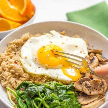 A savory oatmeal bowl with sautéed mushrooms and spinach, topped with a fried egg for an easy but rich and luxurious breakfast!