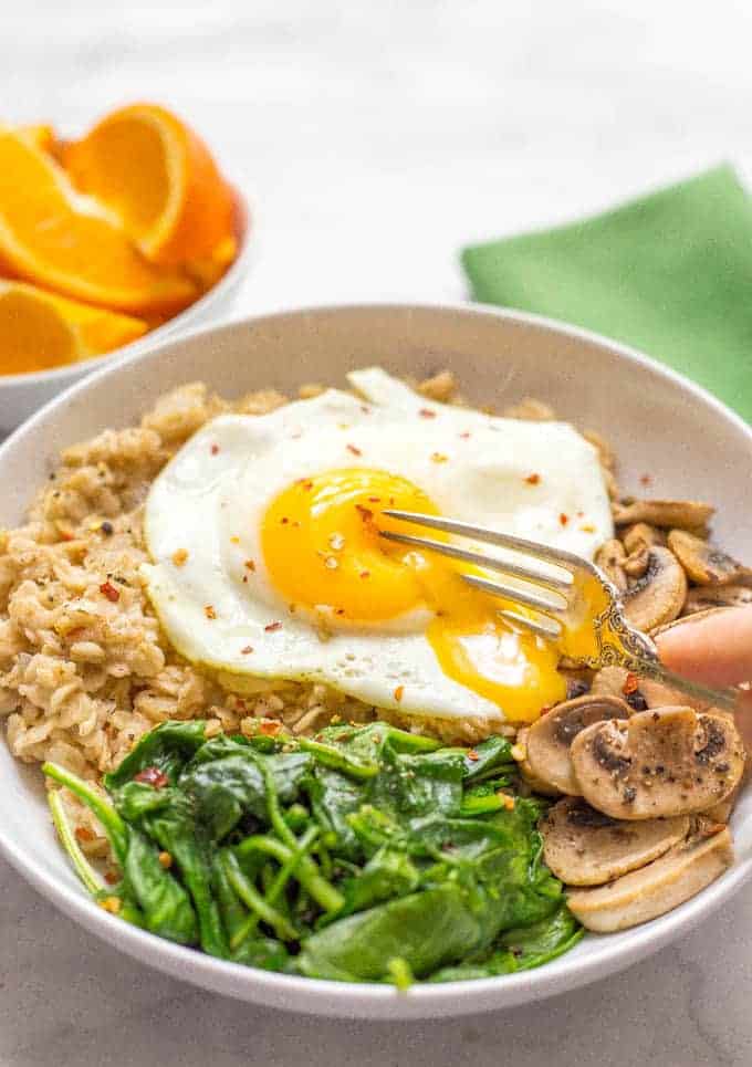 A savory oatmeal bowl with sautéed mushrooms and spinach, topped with a fried egg for an easy but rich and luxurious breakfast!