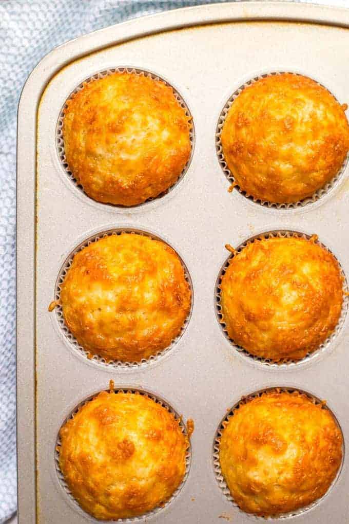 Close up of a muffin tin full of baked, golden brown cheesy cornbread muffins.