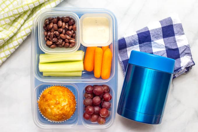 Easy cheesy cornbread muffin packed in compartment lunch box alongside a blue thermos