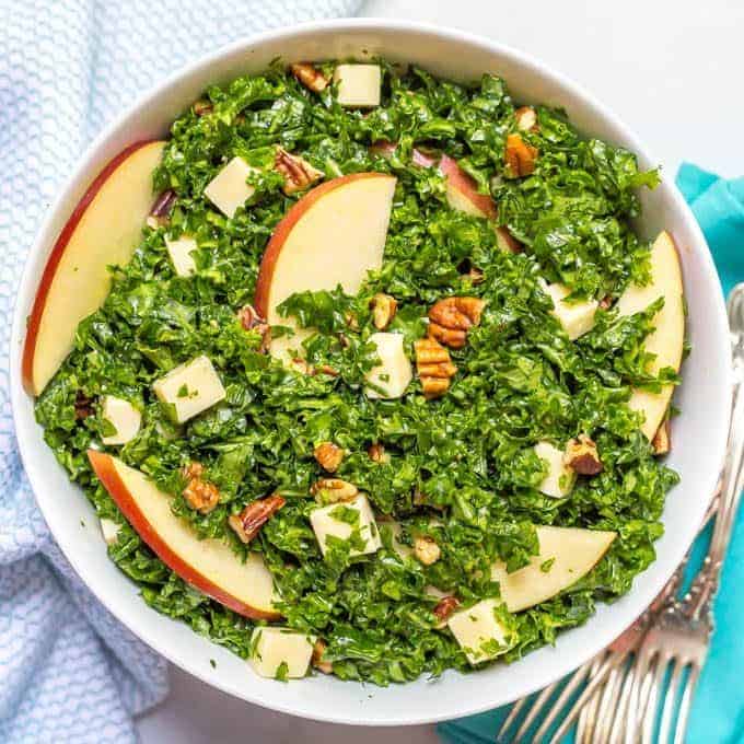 Kale apple salad with cheddar and pecans mixed in bowl