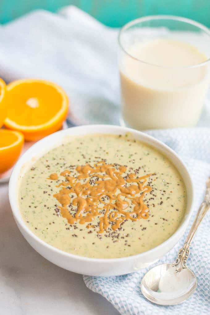 A bowl full of a peanut butter and banana smoothie with spinach with chia seeds and a drizzle of peanut butter on top.