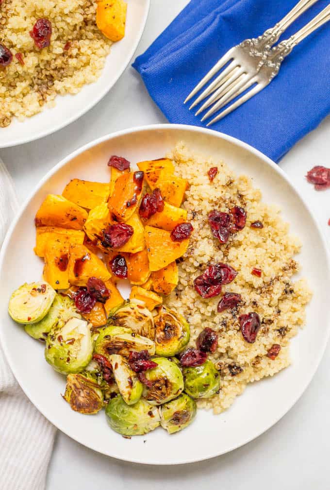 This quinoa bowl with butternut squash and Brussels sprouts is a filling vegetarian dinner that’s topped with dried cranberries and balsamic vinegar for a warm, hearty bowl of delicious! | www.familyfoodonthetable.com