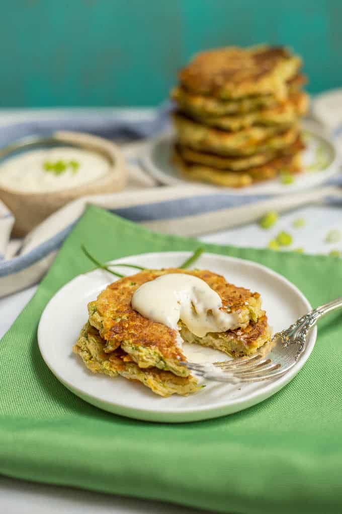 Plate of whole wheat veggie pancakes topped with Ranch dressing and a bite missing