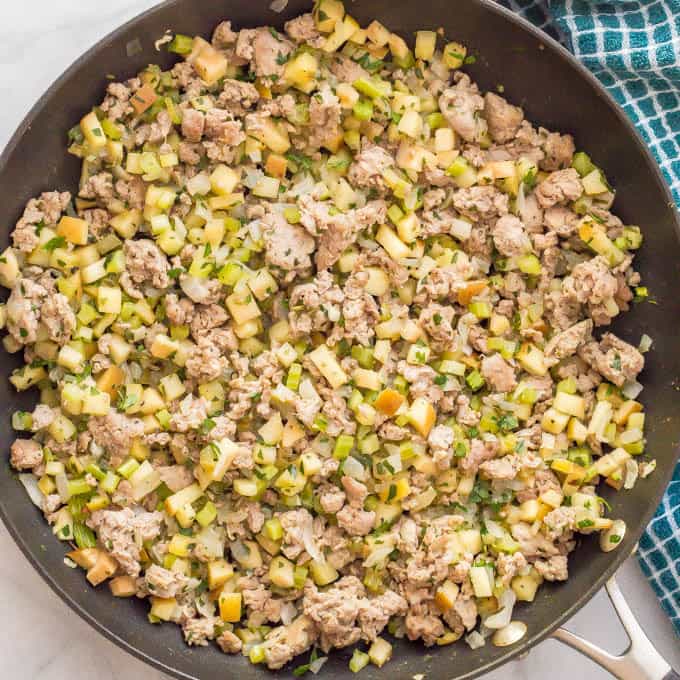 Apple turkey sausage dressing mixture in pan with a towel alongside