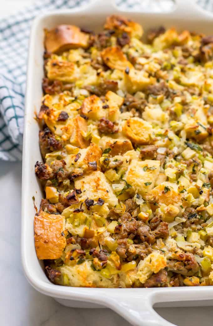 Apple turkey sausage dressing in white casserole pan with a towel at the back