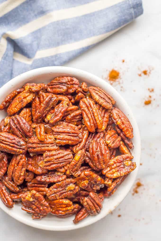 A small white bowl full of pecans coated in a sweet and spicy glaze.