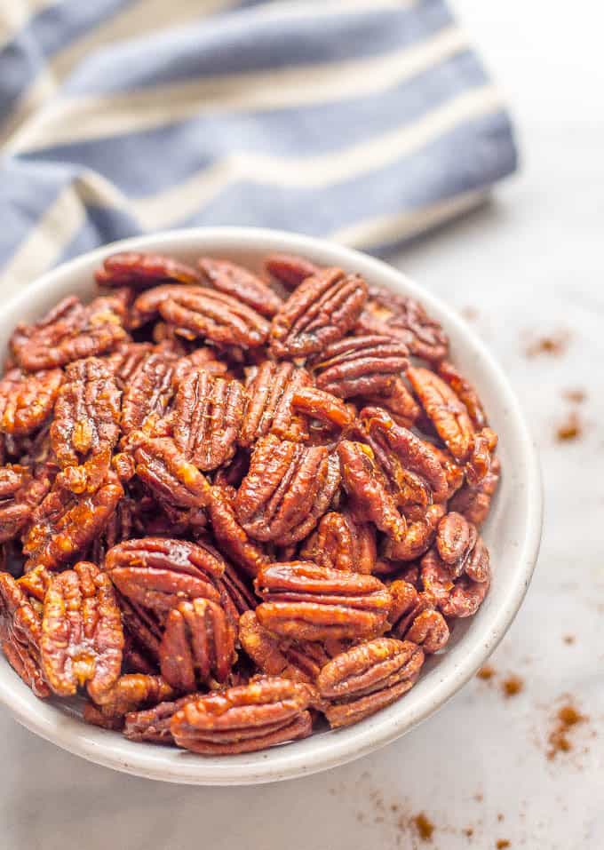 A white bowl full of pecans coated in a sweet and spicy glaze.