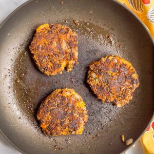 Butternut squash black bean quinoa burgers browned and cooking in pan