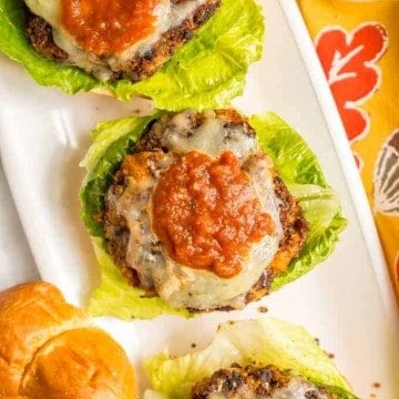 Veggie burgers with black beans served over buns with lettuce and topped with cheese and salsa.