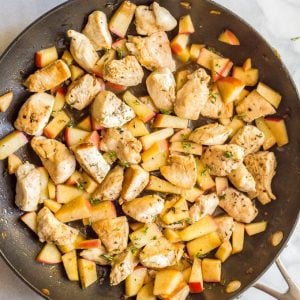 Sautéed chicken and apples in pan with rosemary