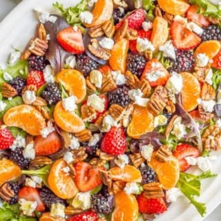 This mixed greens salad with fruit, goat cheese and nuts is perfect for a beautiful side dish or brunch spread! It comes together quickly and is finished with a super easy honey-lime vinaigrette. #easysalad #brunch #vegetarian | www.familyfoodonthetable.com