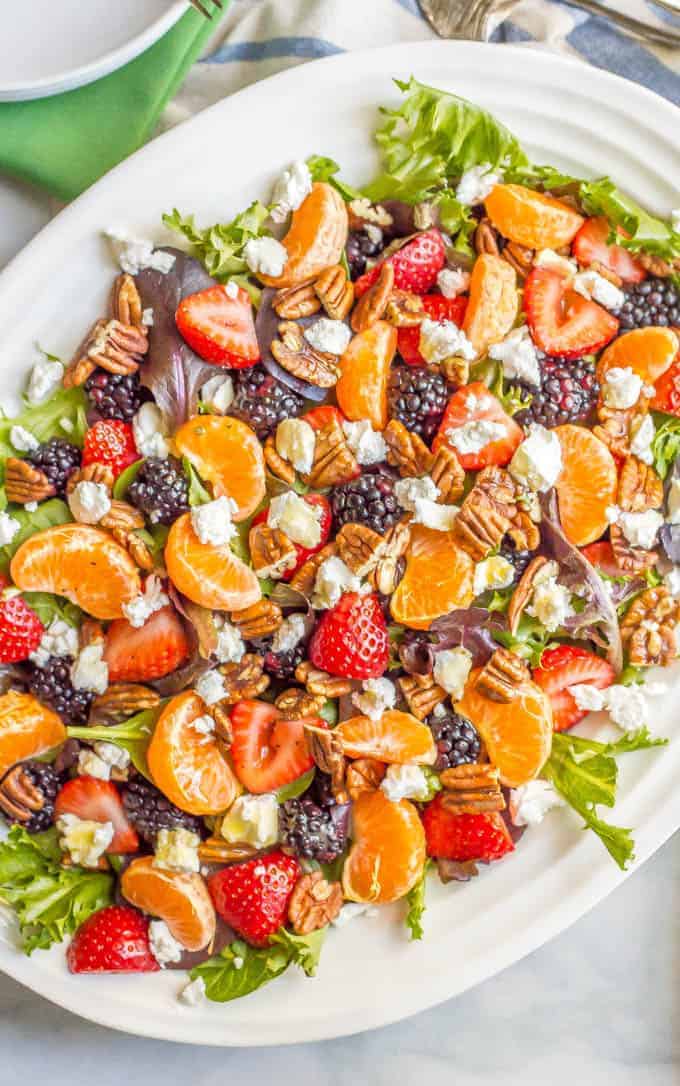 This mixed greens salad with fruit, goat cheese and nuts is perfect for a beautiful side dish or brunch spread! It comes together quickly and is finished with a super easy honey-lime vinaigrette. #easysalad #brunch #vegetarian | www.familyfoodonthetable.com