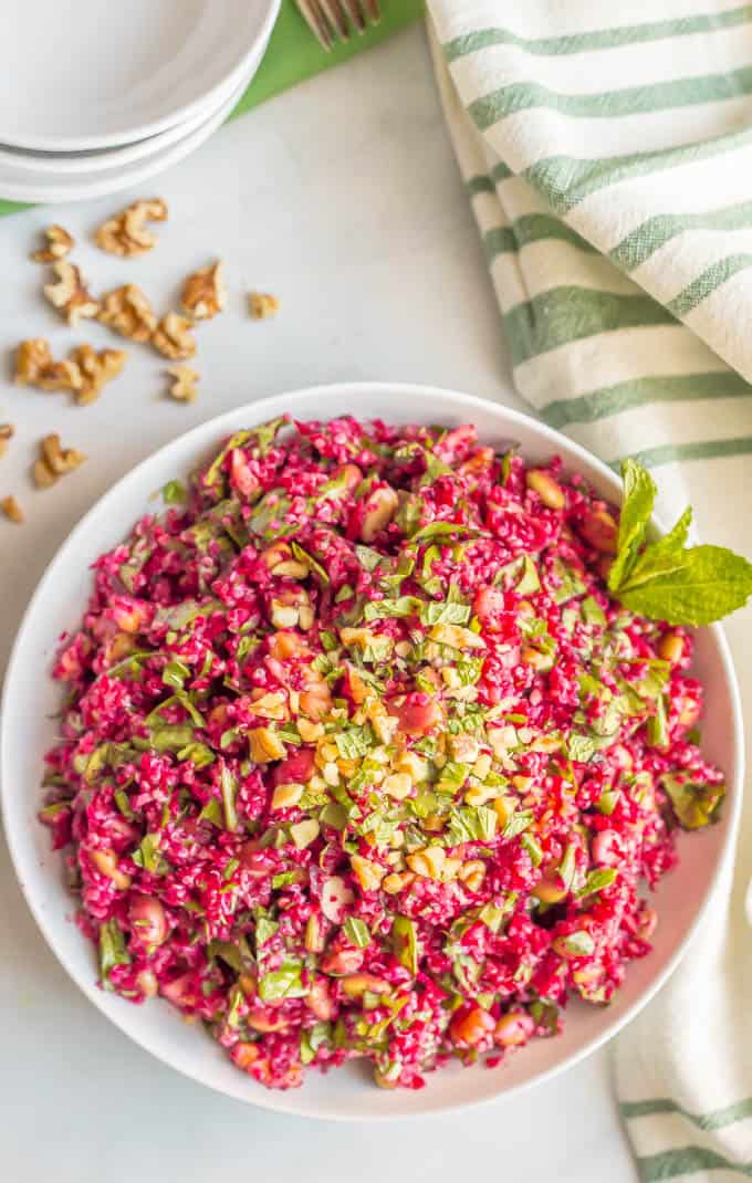 A spiralized beet salad with quinoa, spinach, edamame and walnuts with a sprig of fresh mint on the size.