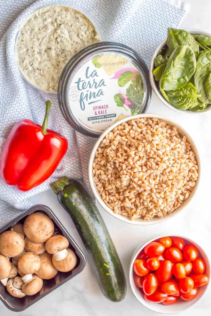 Ingredients to make farro and roasted vegetable grain bowl laid out on a marble surface with a blue and white towel nearby