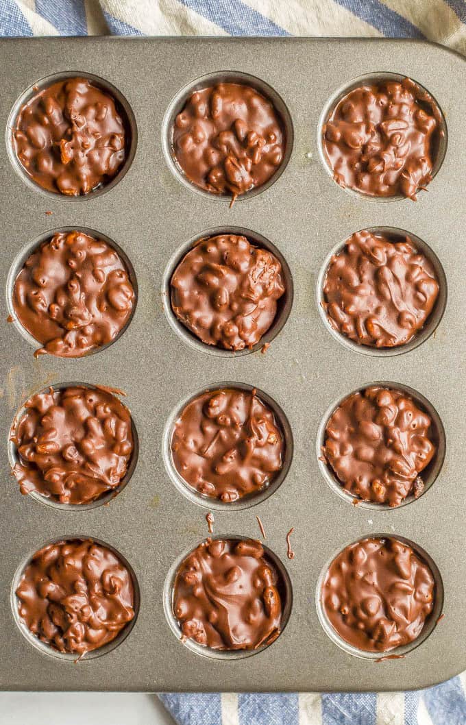 3-ingredient homemade crunch cups in a mini muffin tin after being chilled, with a blue and white striped towel underneath