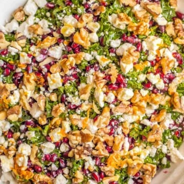 Close up of a colorful winter kale salad with walnuts, feta cheese and pomegranate arils mixed in.