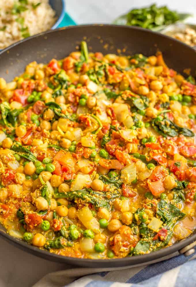 This quick and easy vegetarian curry is loaded with chickpeas, spinach, green peas and plenty of warm spices for a bright, beautiful and flavorful dinner! #curryrecipe #vegetariancurry #easyvegetarian #quickeasydinner | www.familyfoodonthetable.com