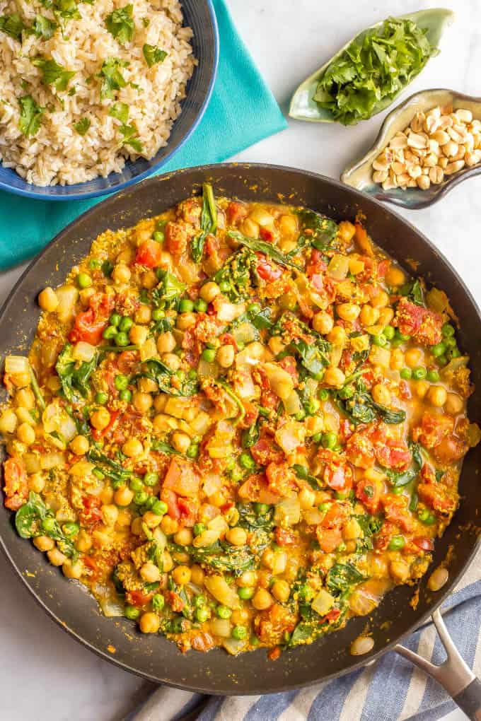 This quick and easy vegetarian curry is loaded with chickpeas, spinach, green peas and plenty of warm spices for a bright, beautiful and flavorful dinner! #curryrecipe #vegetariancurry #easyvegetarian #quickeasydinner | www.familyfoodonthetable.com