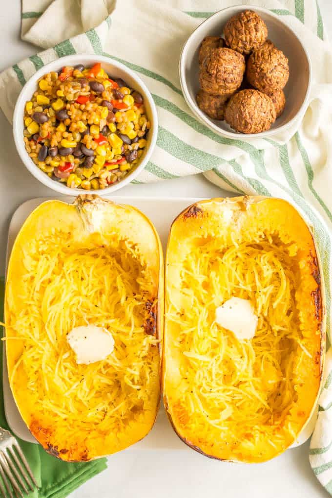 Roasted spaghetti squash with a pat of butter and a bowl of quinoa black bean blend and vegetarian meatballs