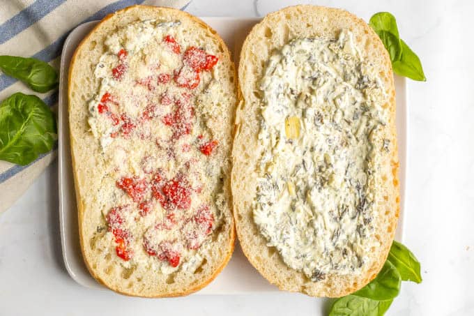 Half loaves of French bread spread with a spinach artichoke mixture and topped with red peppers and Parmesan cheese before being baked