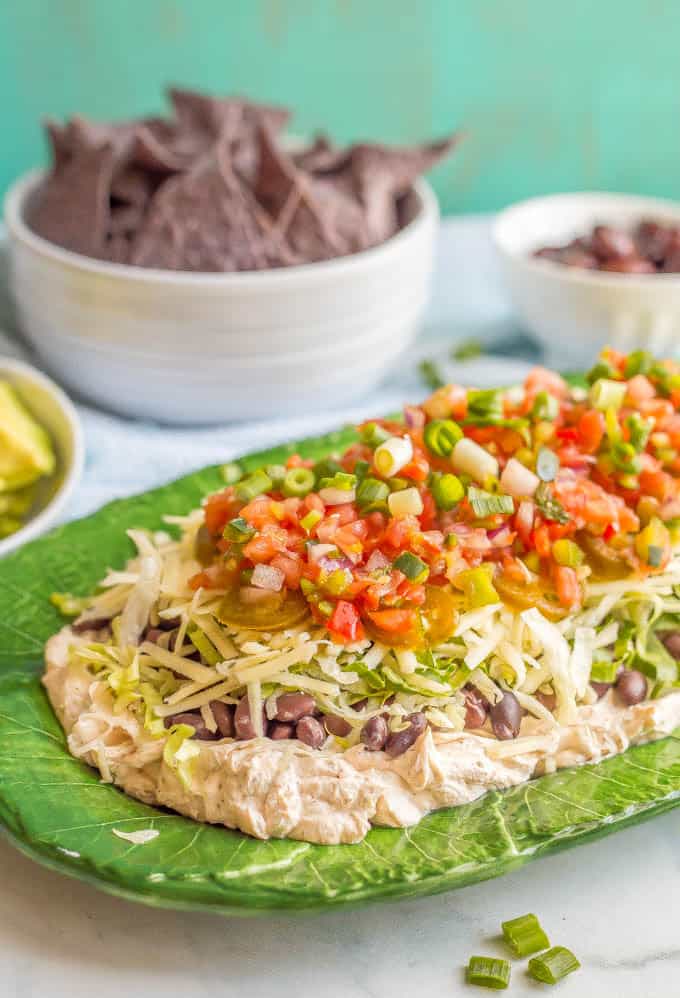 This quick + easy healthy 7-layer Mexican dip is creamy and cheesy, with some crisp, fresh flavors to balance it out. Full of taco flavor and your favorite toppings, this gorgeous dip is perfect for parties! #7layerdip #appetizers #partyfood #cincodemayo #mexicandip