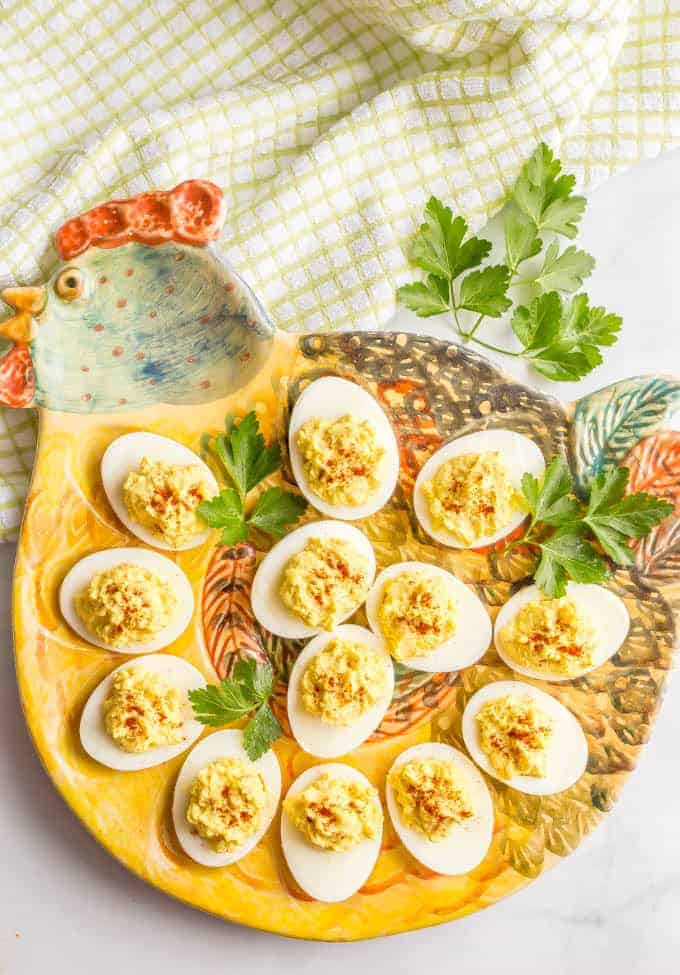 Overhead shot of Mom's classic Southern deviled eggs on a traditional deviled eggs serving platter in the shape of a hen with a green striped towel in the background