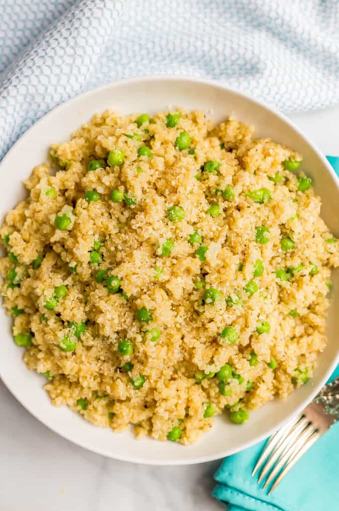 Overhead angle of quinoa with peas and Parmesan in a large white bowl with a turquoise napkin and fork nearby