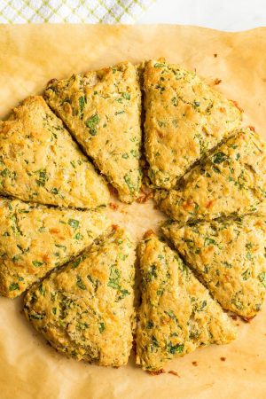 Whole wheat spinach cheddar scones after being baked on a parchment sheet with a green towel