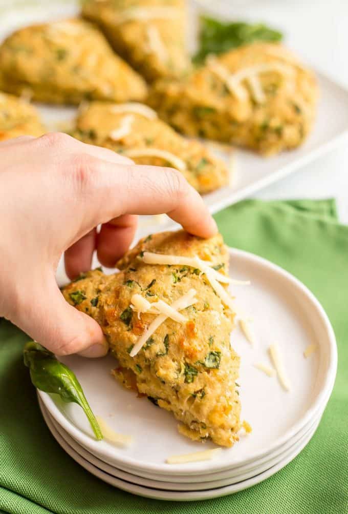 Close up of a single whole wheat spinach cheddar scone being picked up