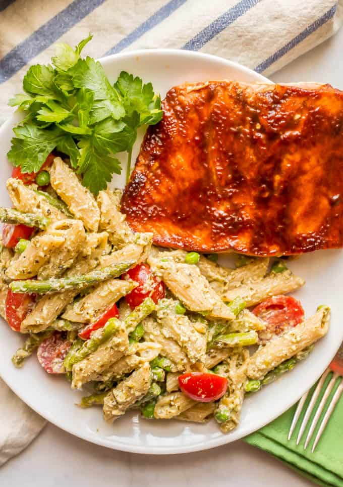 Overhead photo of creamy pesto pasta with asparagus and peas with salmon dinner plate