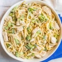Healthy Chicken Alfredo with Broccoli in a large white serving dish with a blue napkin
