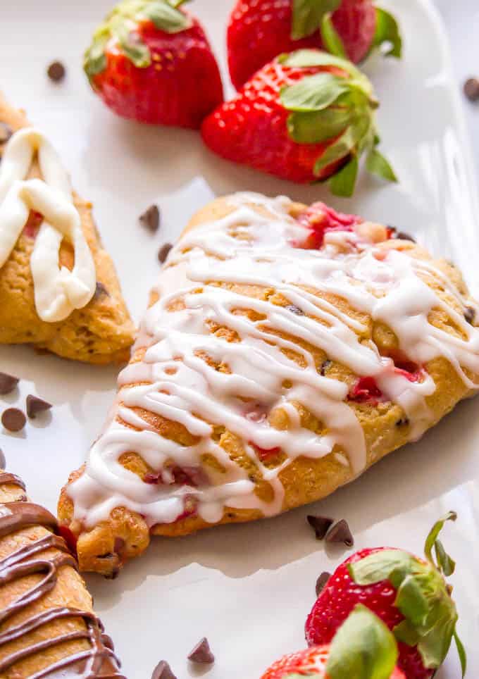 Close-up of a healthy strawberry scone with a lemon glaze drizzled on top and fresh strawberries to the side