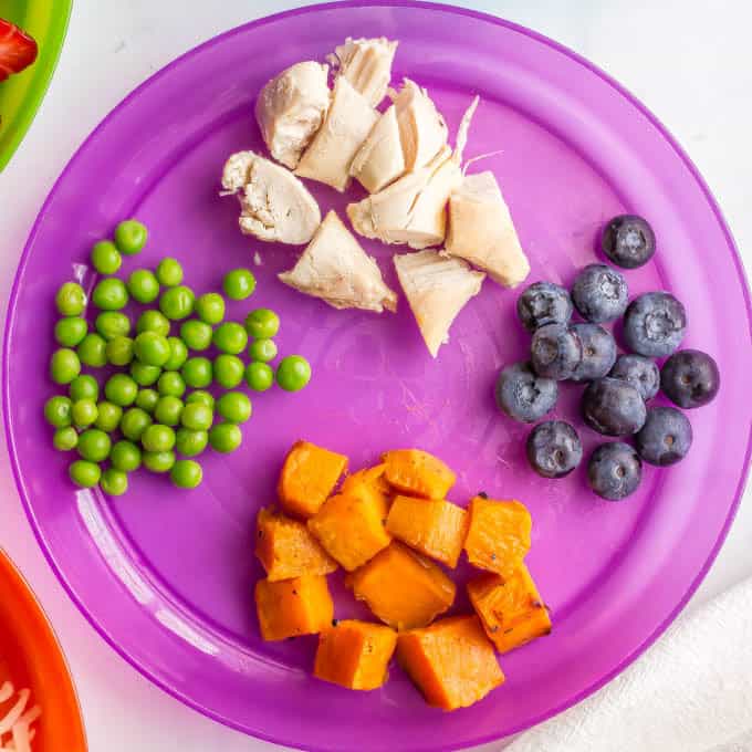 Purple kids plate with peas, chicken, blueberries and sweet potato