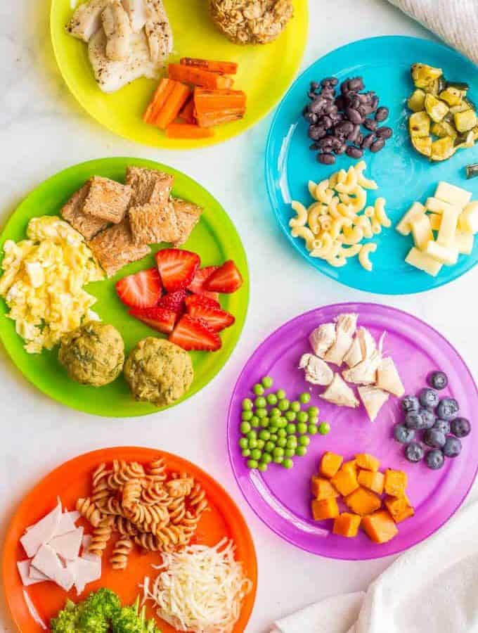 Overhead image of colorful plates with a variety of healthy baby finger foods and toddler finger foods