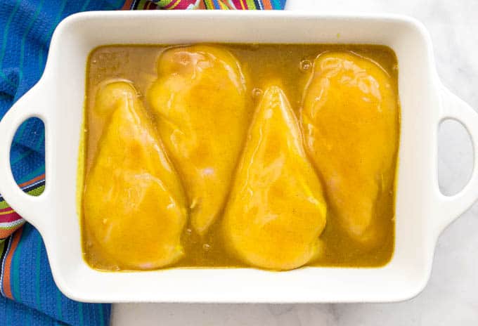 Overhead shot of honey butter chicken in a white casserole dish before being cooked