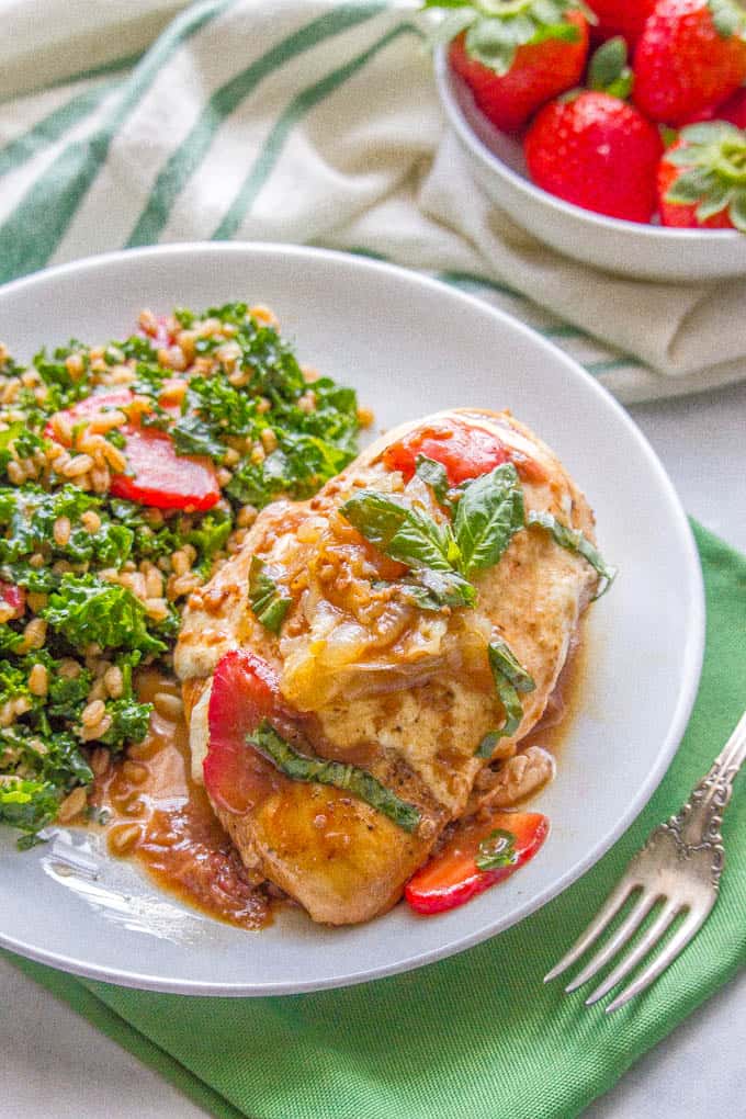 Dinner plate with strawberry balsamic chicken with mozzarella being served with a farro kale salad