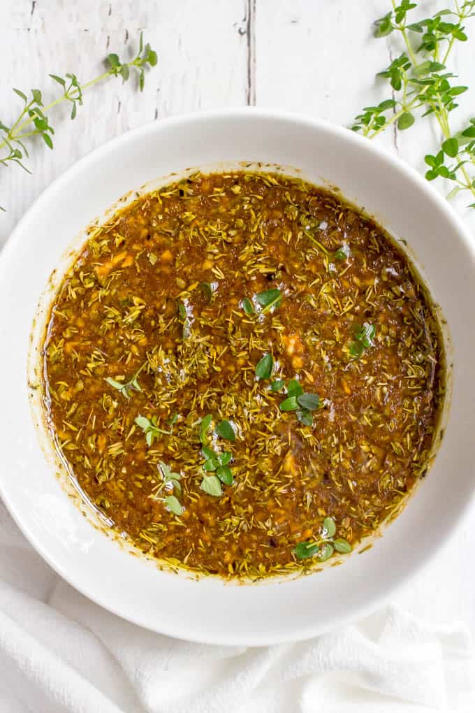 Balsamic herb grilled chicken marinade in a white bowl with springs of thyme nearby