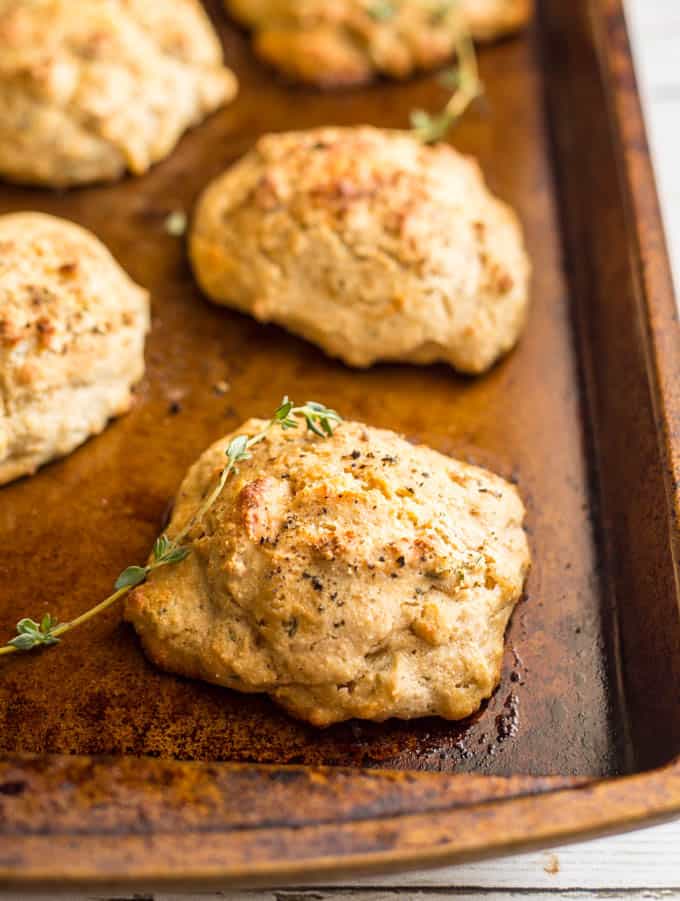 Close-up of Parmesan herb drop biscuits on baking tray with thyme scattered about