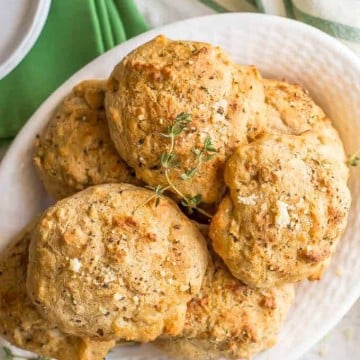 Homemade drop biscuits with Parmesan and herbs piled in a white serving bowl.