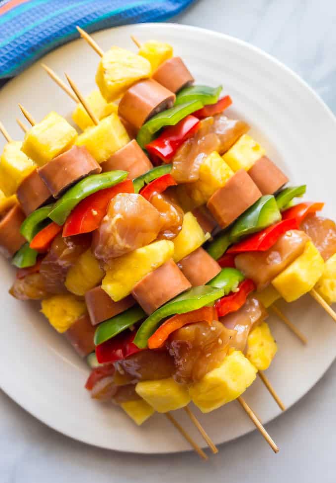 Teriyaki chicken kabobs on a white plate threaded onto skewers before being grilled