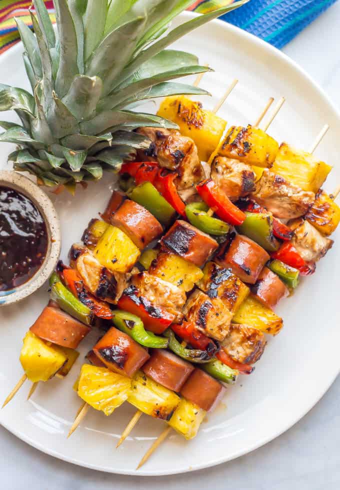 Grilled teriyaki chicken kabobs on a white plate with a small bowl of teriyaki sauce nearby